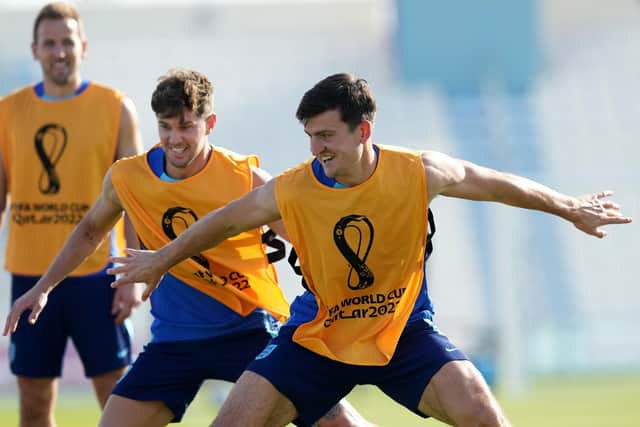 PARTNERS: Team-mates John Stones (left) and Harry Maguire enjoy a joke during an England training session at the Al Wakrah Sports Complex, Qatar. Picture: Martin Rickett/PA