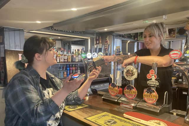 Claudia Bowes, Scarborough News reporter, being handed the old purse from Tara Giles, owner of the Belle Vue pub, on behalf of her mother.