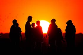 A crowd of people watch the setting sun from a hill in Ealing during August's heatwave.