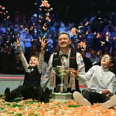 England's Kyren Wilson poses with the trophy and his sons Bailey (L) and Finley (R) after victory over Wales' Jak Jones. (Photo by Oli SCARFF / AFP) (Photo by OLI SCARFF/AFP via Getty Images)