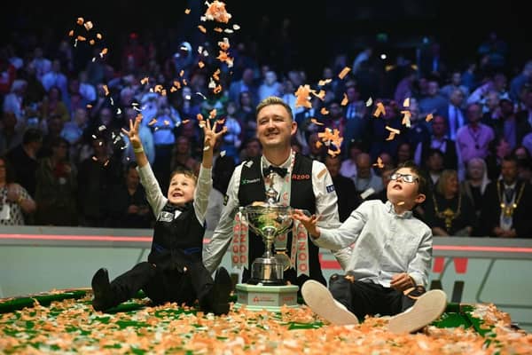 England's Kyren Wilson poses with the trophy and his sons Bailey (L) and Finley (R) after victory over Wales' Jak Jones. (Photo by Oli SCARFF / AFP) (Photo by OLI SCARFF/AFP via Getty Images)