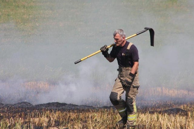 A firefighter on duty walks in front of a wildfire in South Yorkshire.