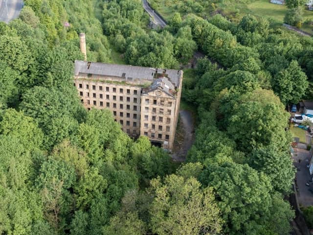 The derelict mill sits in a wooded valley