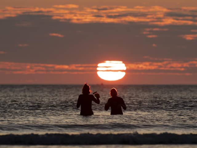 Two woman take a dip in the sea off Cayton Bay in Scarborough as the sun rises on the Summer Solstice. Picture: Danny Lawson/PA Wire
