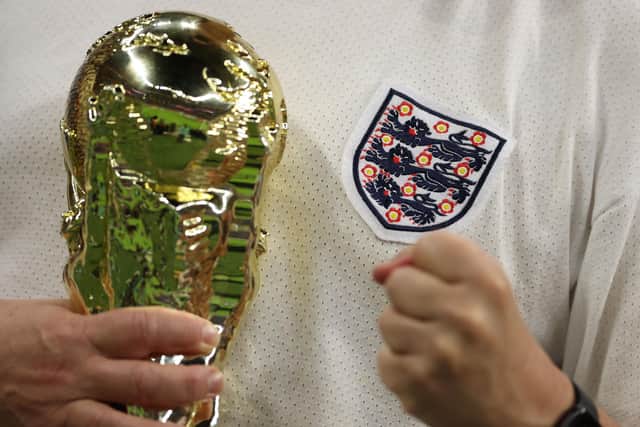 An England supporter holds a replica of he World Cup trophy ahead of the start of the Qatar 2022 World Cup round of 16 football match between England and Senegal at the Al-Bayt Stadium in Al Khor, north of Doha on December 4, 2022. (Photo by ADRIAN DENNIS/AFP via Getty Images)