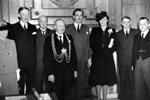 This photograph is taken in the Lord Mayor's parlour of Leeds Civic Hall in front of the great fireplace in July 1941. It is on the occasion of the visit to Leeds of Anthony Eden, Foreign Secretary, seen at the centre. His wife, Beatrice stands beside him. In the foreground is the Lord Mayor of Leeds, Alderman Willie Withey.