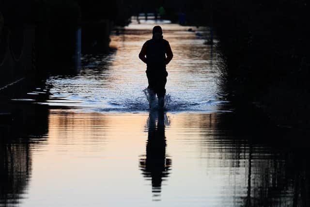 People walk through floodwater on a flooded street. (Pic credit: Daniel Leal / AFP via Getty Images)