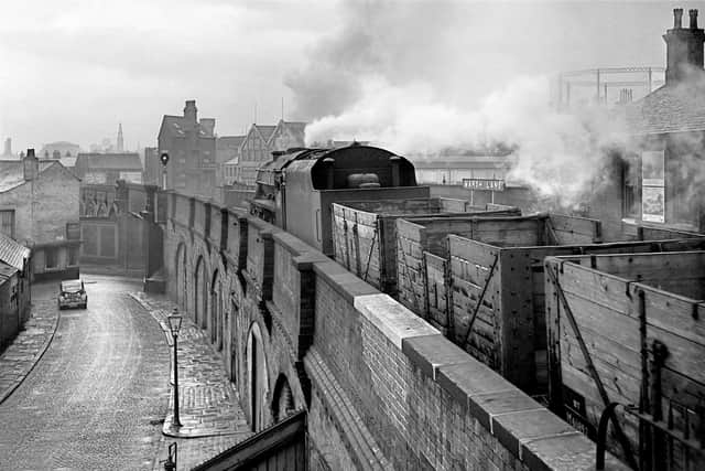In a classic Leeds urban setting, a ‘Black Five’ loco hauls an empty freight train over the viaduct and past the site of Marsh Lane station.