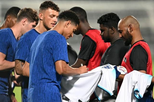 POLITICAL GESTURE: England's rising star Jude Bellingham (foreground) signs a jersey for migrant workers at the Al Wakrah Stadium in Doha