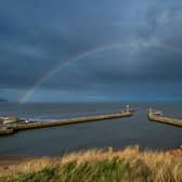 A rainbow stretching over Whitby's harbour walls brightens up the dark sky. PIC: James Hardisty