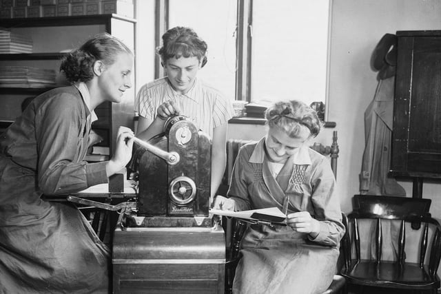 Three female students at the Sheffield Central Day Commercial College learn to operate a duplicating machine for reproducing notes in September 1936.