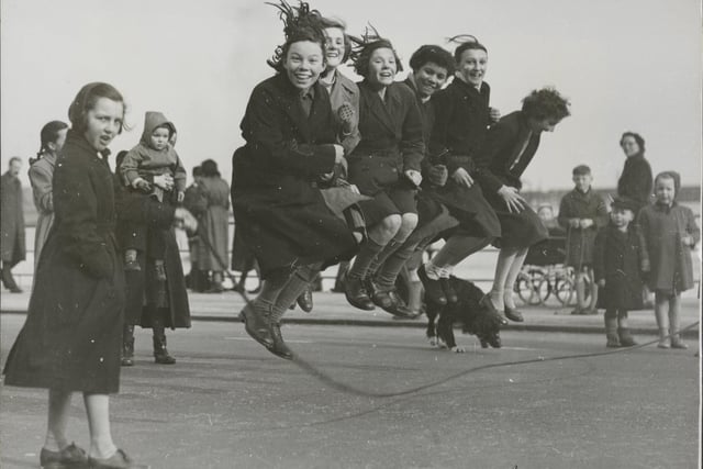 One of the parties enjoying a huge skip, on the Foreshore road, (Lt to Rt) Kathleen Ashwell, (turning) Pauline Hammond, Margaret Lawrence, Lorna Leach, Rosemary Reid, Eileen Smith, Gillian Green, Sylvia Green, and at the far end turning, Kathleen Ashwell, Scarborough. 03 March, 1954.