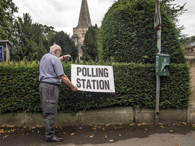 A man adjusts a polling station sign at Saint Martin Church in Womersley. PIC: Danny Lawson/PA Wire
