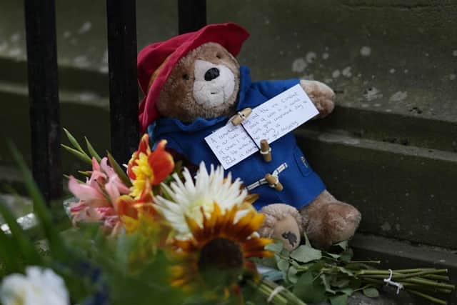 A small Paddington Bear toy and message is left amongst flowers and tributes outside the Palace of Holyroodhouse in tribute to Queen Elizabeth II. (Pic credit: Christopher Furlong / Getty Images)