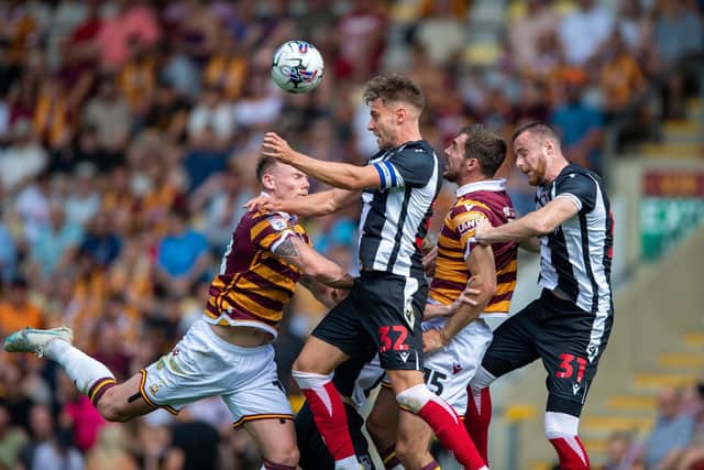 Grimsby Town striker Danny Rose beats Bradford City defender San Stubbs (centre) to a high ball. Picture: Bruce Rollinson