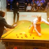 A Just Stop Oil protester is removed after jumping on the table and throwing orange powder during the match between Robert Milkins against Joe Perry during day three of the Cazoo World Snooker Championship at the Crucible Theatre, Sheffield. Picture date: Monday April 17, 2023.