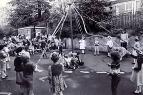 Children of Hucklow First School, Firth Park, Sheffield, dancing round the maypole before an audience of parents in the schoolyard.
18th May 1983