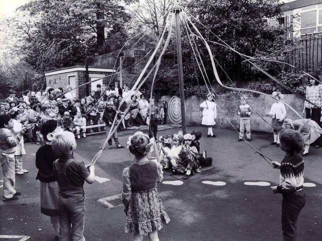 Children of Hucklow First School, Firth Park, Sheffield, dancing round the maypole before an audience of parents in the schoolyard.18th May 1983
