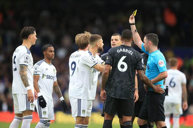 English referee Chris Kavanagh (R) shows a yellow card to Arsenal's Brazilian defender Gabriel Magalhaes (C) having earlier shown his a red card during the English Premier League football match between Leeds United and Arsenal at Elland Road in Leeds, northern England on October 16, 2022. (Photo by LINDSEY PARNABY/AFP via Getty Images)