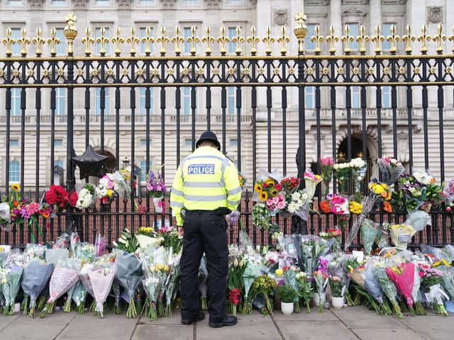 A police officer looks at flowers laid outside Buckingham Palace, London, following the death of Queen Elizabeth II.