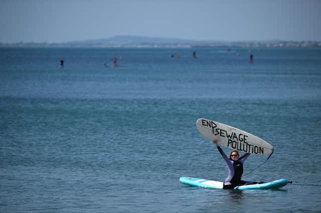 A Surfers Against Sewage activist holds a board reading "End sewage pollution" during a protest against sewage pollution in Brighton, southern England, on May 20, 2023. England's privatised water companies pledged this week to make massive investments to stop raw sewage being pumped into waterways as concerns mount about water quality and laxer environmental protections post-Brexit. (Photo by Ben Stansall / AFP) (Photo by BEN STANSALL/AFP via Getty Images)
