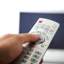 A person holding a TV remote control.
