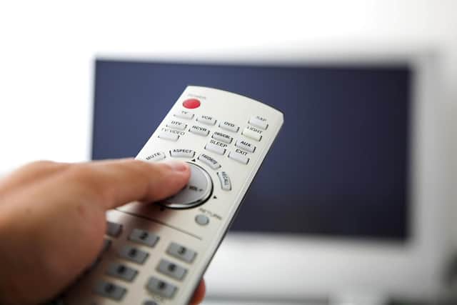 A person holding a TV remote control.