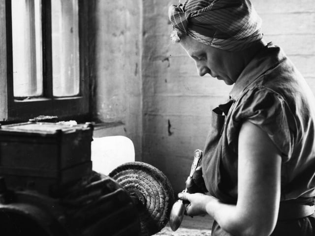 An employee at a factory in Sheffield polishes a spoon on a wheel, one of a sequence of abrasive operations in the cutlery-making process, in September 1955.