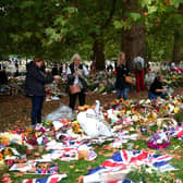 Members of the public help remove the plastic wrapping from the flowers in Green Park in memory of Queen Elizabeth II on September 13, 2022 in London. (Photo by Shaun Botterill/Getty Images)