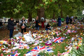 Members of the public help remove the plastic wrapping from the flowers in Green Park in memory of Queen Elizabeth II on September 13, 2022 in London. (Photo by Shaun Botterill/Getty Images)