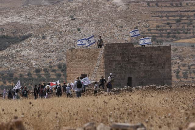 Israeli settlers put up Israeli flags on a Palestinian structure. PIC: AP Photo/Mahmoud Illean