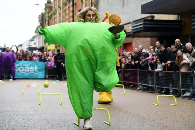 A woman in a puffy green costume racing with her pancake.