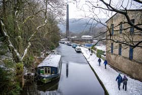 Walkers on the towpath beside the Rochdale Canal in Hebden Bridge as snow hit the region. PIC: Tony Johnson.