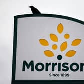 A bird is perched on a Morrisons sign. (Pic credit: Tolga Akmen / Getty Images)