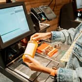 A customer scans and pays for a bottle of juice from a supermarket at an automated self-service checkout terminal. PIC: Adobe