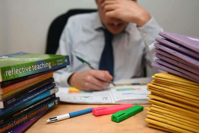 A school teacher looking stressed next to piles of classroom books. PIC: PA Wire/PA Wire