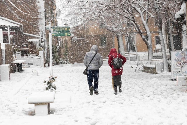 Two people walk down a snow-covered street in the mountain village of Valldemossa during a heavy snow-fall, on the Spanish Balearic island of Mallorca, on February 27, 2023.(Photo by JAIME REINA/AFP via Getty Images)