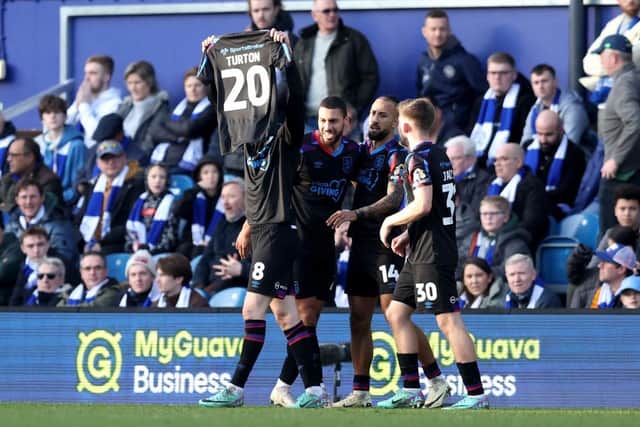 LONDON, ENGLAND - JANUARY 28: Jack Rudoni of Huddersfield Town celebrates scoring his team's first goal whilst holding the shirt of injured teammate Oliver Turton of Huddersfield Town (not pictured) during the Sky Bet Championship match between Queens Park Rangers and Huddersfield Town at Loftus Road on January 28, 2024 in London, England. (Photo by Richard Pelham/Getty Images)