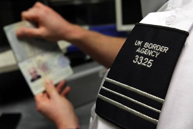 A UK Border Agency officer checks a passport at Gatwick Airport. PIC: Steve Parsons/PA Wire
