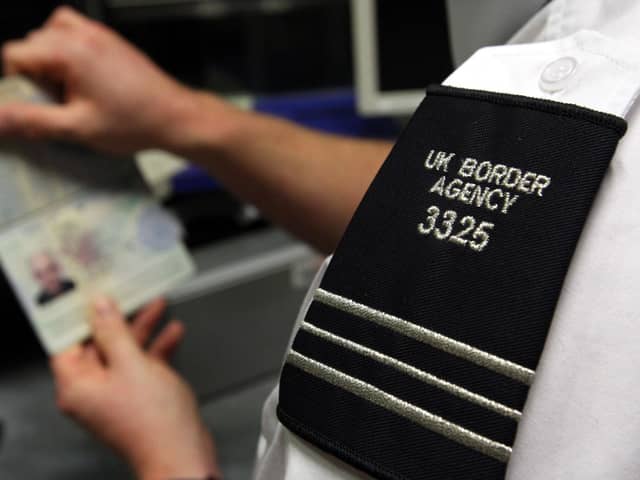 A UK Border Agency officer checks a passport at Gatwick Airport. PIC: Steve Parsons/PA Wire