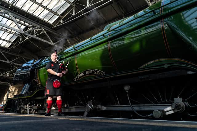 A member of the Red Hot Chili Pipers poses in front of the Flying Scotsman at Waverley Station on February 24, 2023 in Edinburgh, Scotland. Over the last one hundred years it has become world-famous and attracts thousands of visitors each year to its home at the National Railway Museum in York. Photo by Peter Summers/Getty Images.