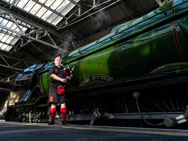 A member of the Red Hot Chili Pipers poses in front of the Flying Scotsman at Waverley Station on February 24, 2023 in Edinburgh, Scotland. Over the last one hundred years it has become world-famous and attracts thousands of visitors each year to its home at the National Railway Museum in York. Photo by Peter Summers/Getty Images.