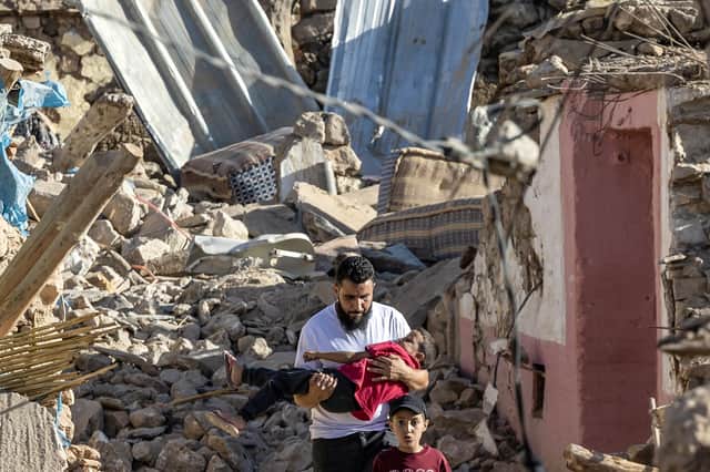 A man carries a boy as he walks past destroyed houses after an earthquake in the mountain village of Tafeghaghte, southwest of Marrakesh, on September 9, 2023. Moroccans on September 10 mourned the victims of a devastating earthquake that killed more than 2,000 people, as rescue teams raced to find survivors trapped in the rubble of flattened villages. (Photo by Fadel SENNA / AFP) (Photo by FADEL SENNA/AFP via Getty Images)