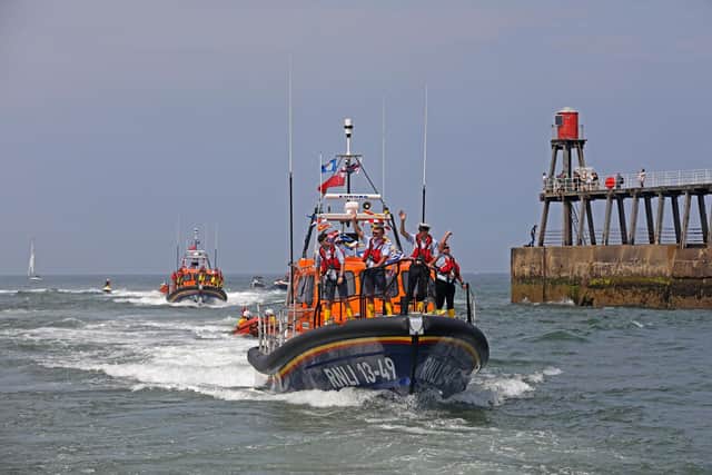 The crew wave to well wishers as the lifeboat enters Whitby harbour

(Pic: RNLI/Ceri Oakes)