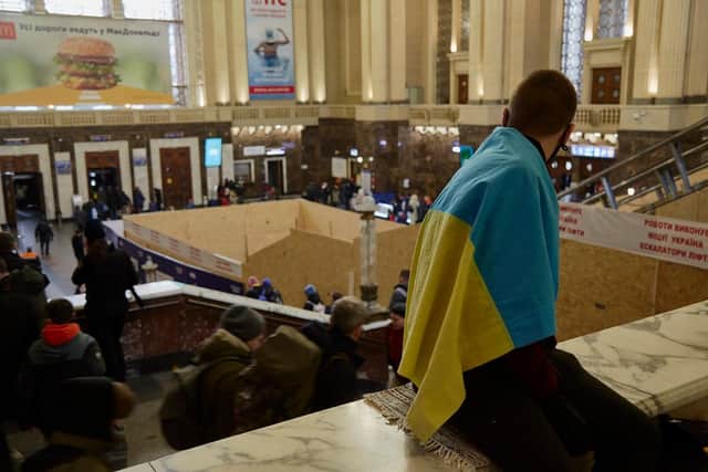 A man wearing the Ukrainian flag is waiting for a train at the train station as all trains are delayed in Kyiv. (Pic credit: Pierre Crom / Getty Images)