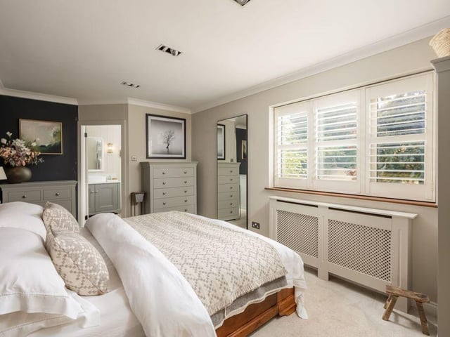 The principal bedroom overlooks the rear garden through a window fitted with plantation shutters.