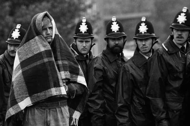 A striking miner with a blanket over his head against the rain, stands in front of a line of police officers near the Orgreave coking plant. PIC: Tom Stoddart/Getty Images