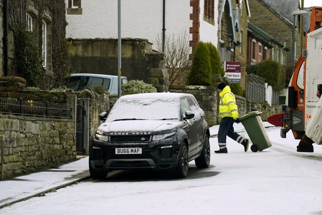 A refuse collector clears the bins in snowy conditions in Briggswath, North Yorkshire. (Photo credit: Owen Humphreys/PA Wire)