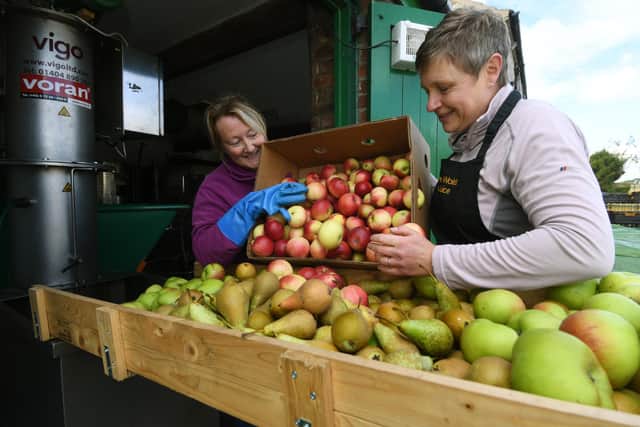 Jane helps customer Helen Harrison with her fruit she is having pressed.