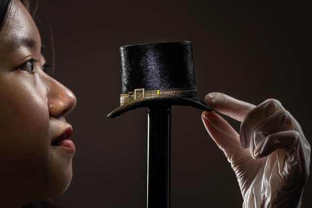 Kelly Tang views a tiny top hat from a collection of vintage miniature millinery, made by Leeds hatter John Craig in the early 1900s, which are being documented and conserved by museum experts and volunteers at the Leeds Discovery Centre. Photo credit: Danny Lawson/PA Wire
